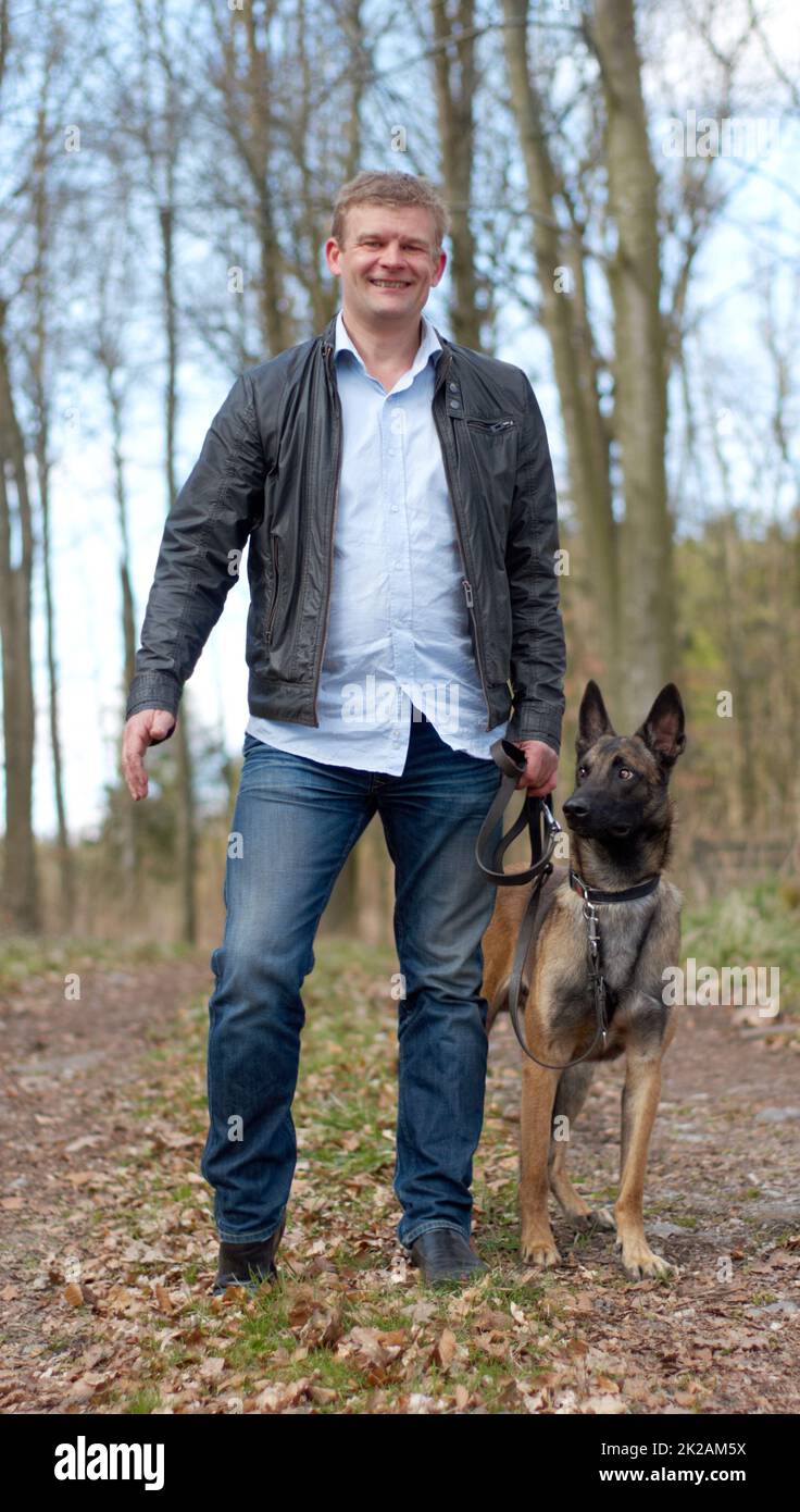 Out with my best friend. Shot of a man going for a walk with his dog in the woods. Stock Photo