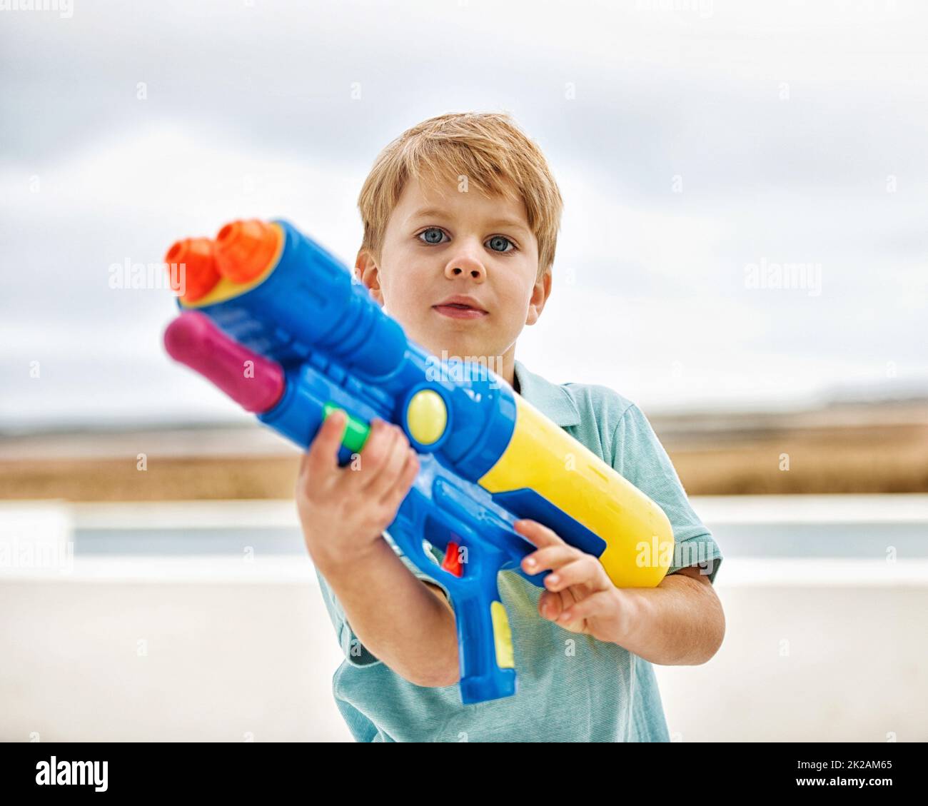 Im a professional water shooter. Portrait of a cute young boy holding a water gun outside. Stock Photo