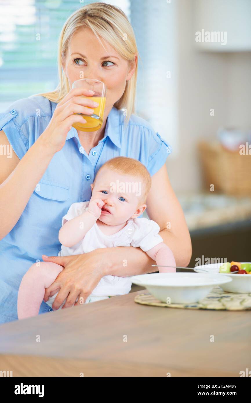 Mommy and baby need their sustenance. A mother and her adorable baby girl sitting in the kitchen enjoying breakfast. Stock Photo