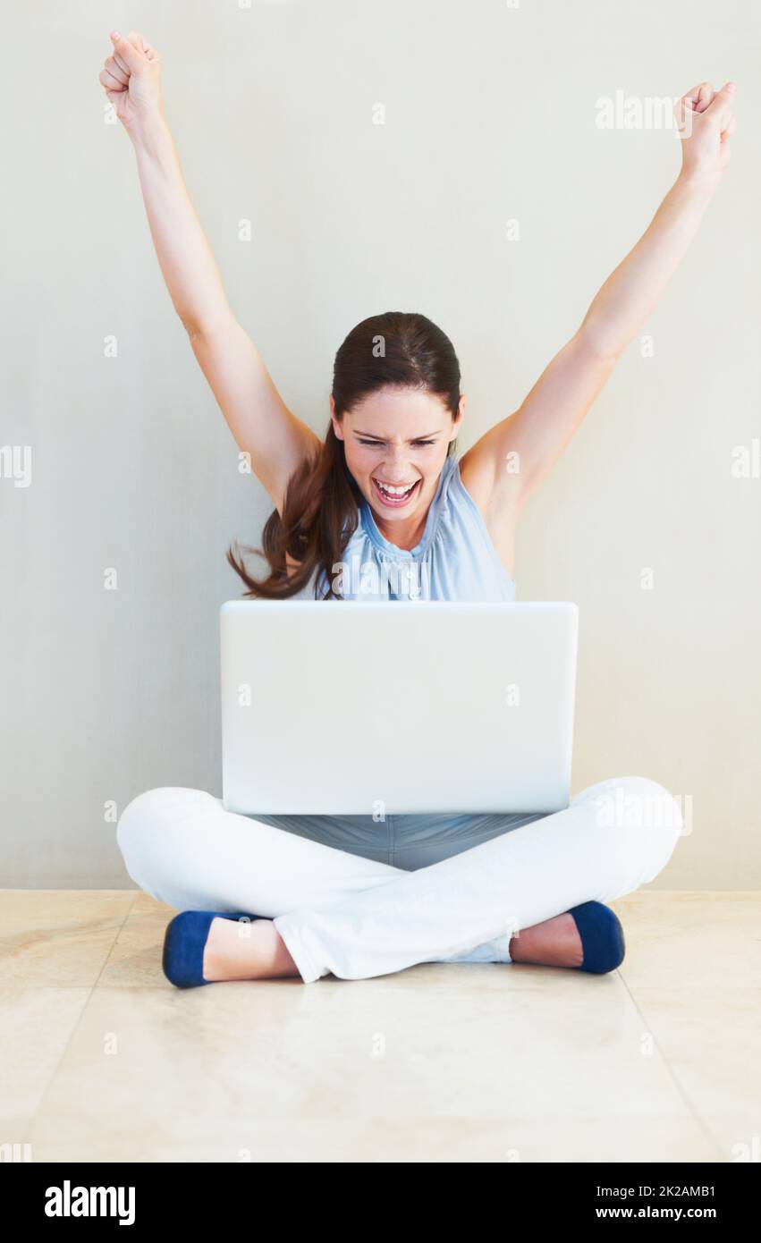Yes. A pretty young woman cheering while looking at her laptop screen. Stock Photo