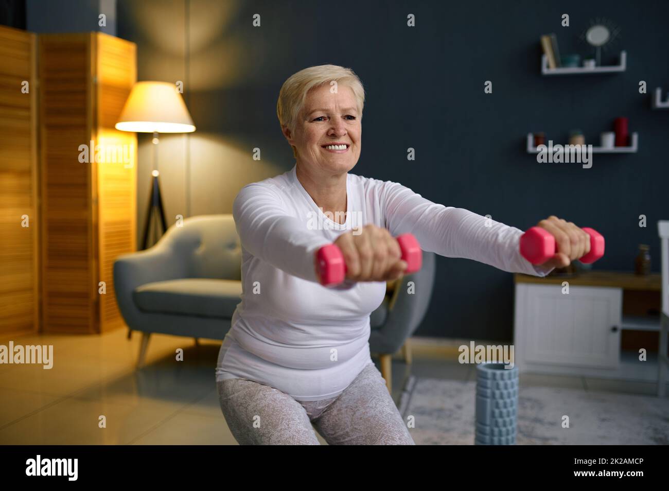 Senior woman training with dumbbells at home Stock Photo