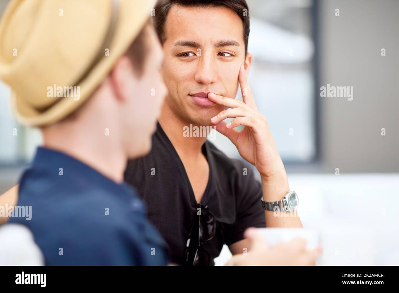Talking to your best friend is sometimes all the therapy you need. Shot of a young man listening to his friend talk. Stock Photo