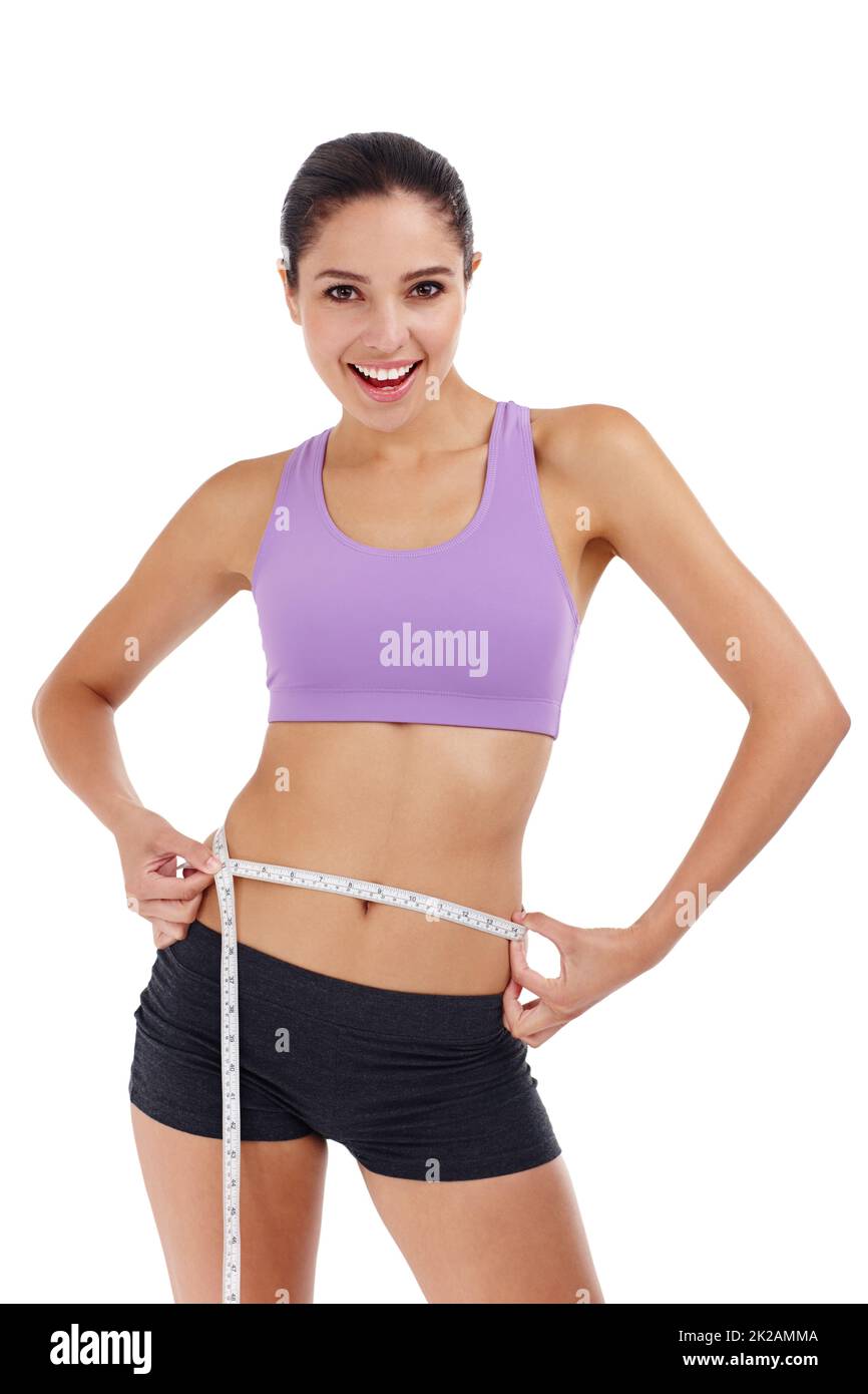 Slimming down for summer. Three quarter length shot of an attractive young woman in gym clothes measuring her waist. Stock Photo
