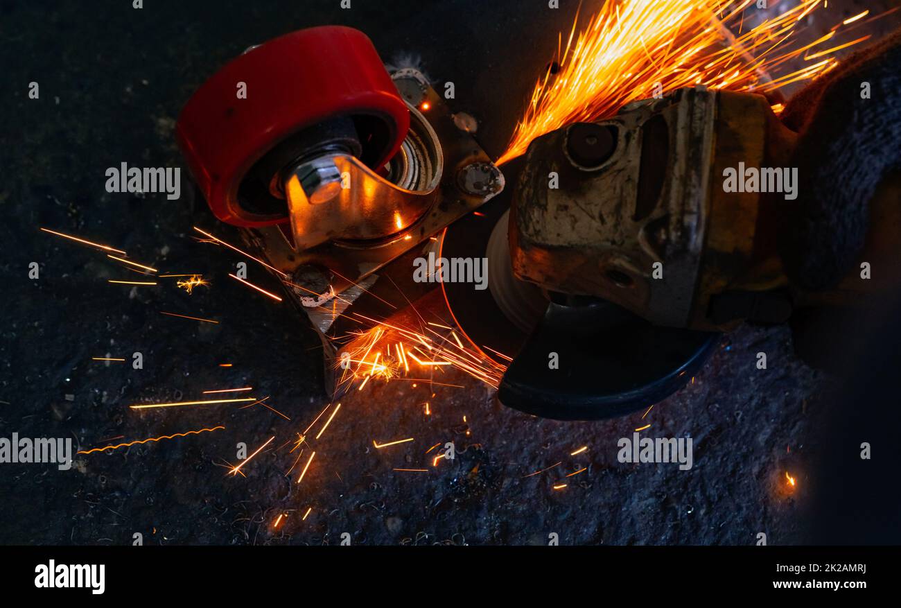 Industrial worker using angle grinder cutting metal. Worker working