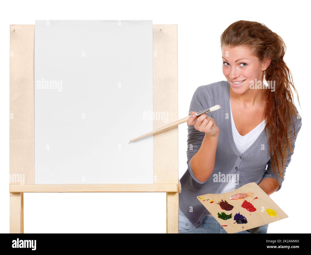 The creative juices are about to flow.... Studio shot of a young woman holding a palette and brush and standing with an easel. Stock Photo