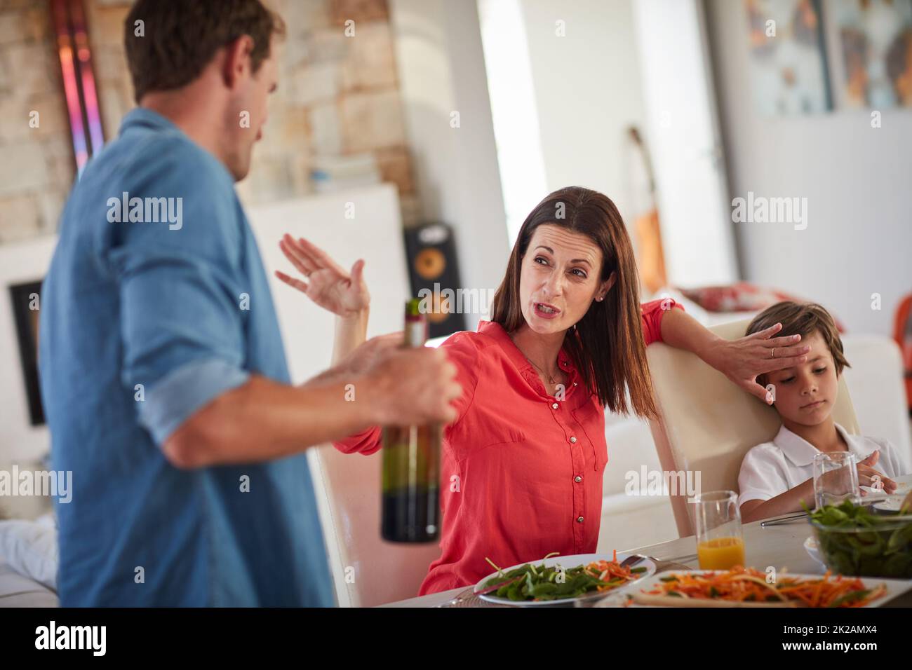 Do you want your children to see you like this. Shot of a drunk man and his wife arguing in front of their children during lunch. Stock Photo