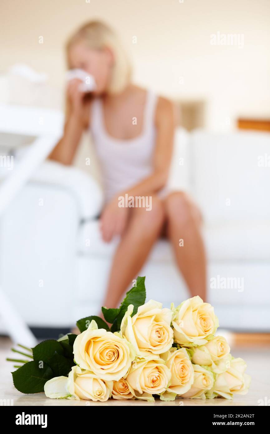 In Russia, Yellow roses are never a good sign. A young woman sneezing in the background with roses lying on the floor. Stock Photo