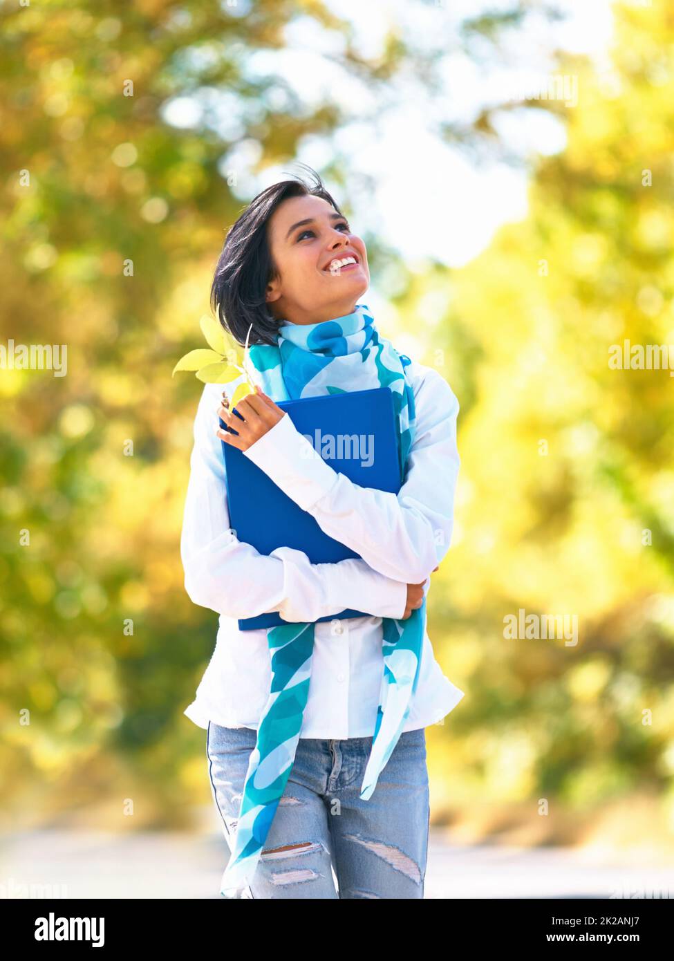 Autumn stroll. A young woman strolling down the street admiring the autumn leaves. Stock Photo