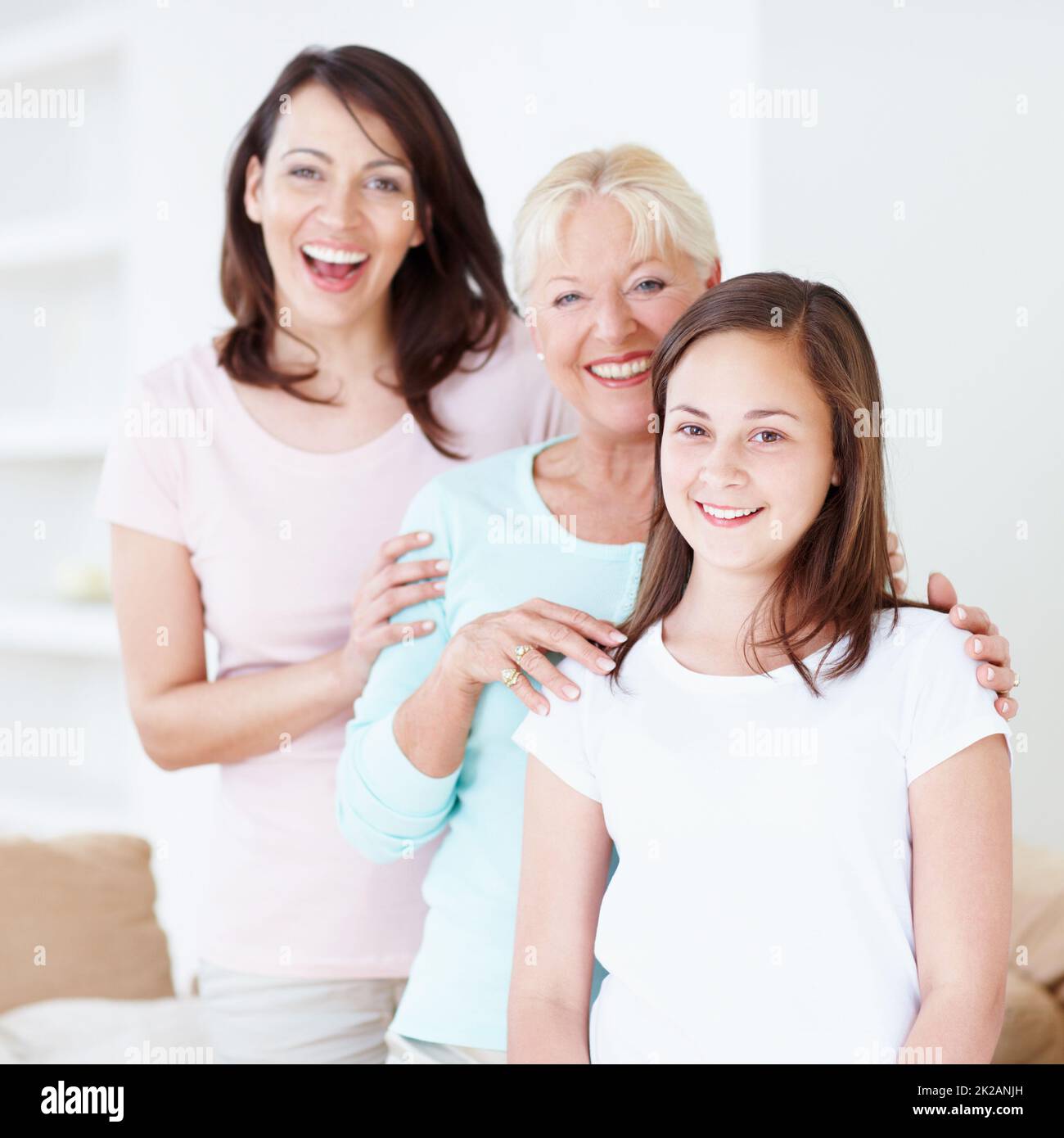 Lining up for love and laughter. Portrait of a granddaughter, mother and grandmother laughing happily while holding one another in a line. Stock Photo