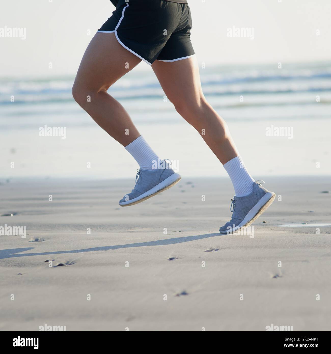 Dont stop until youve reached your goal. Cropped shot of an unrecognizable young man running on the beach. Stock Photo