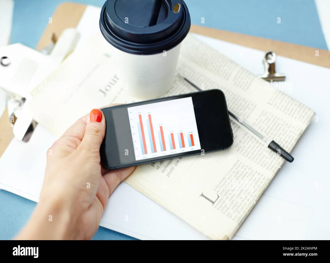 One last look at the numbers. Hand holding smartphone with bar chart on