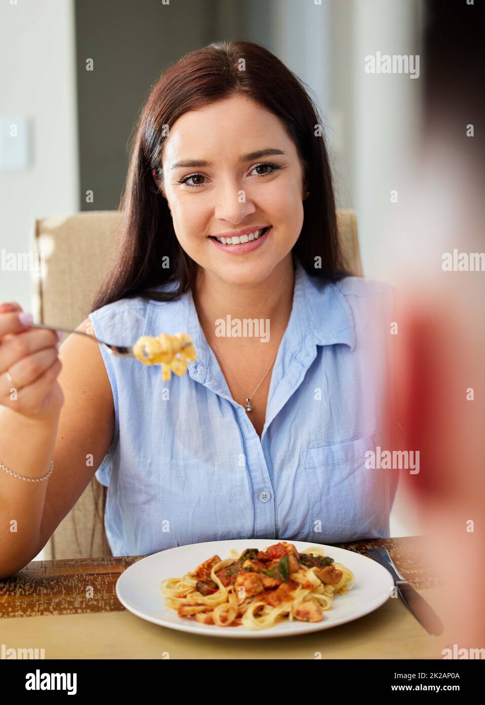 Eating a dish I love is the highlight of my day. Shot of a young woman sitting down to eat at home. Stock Photo