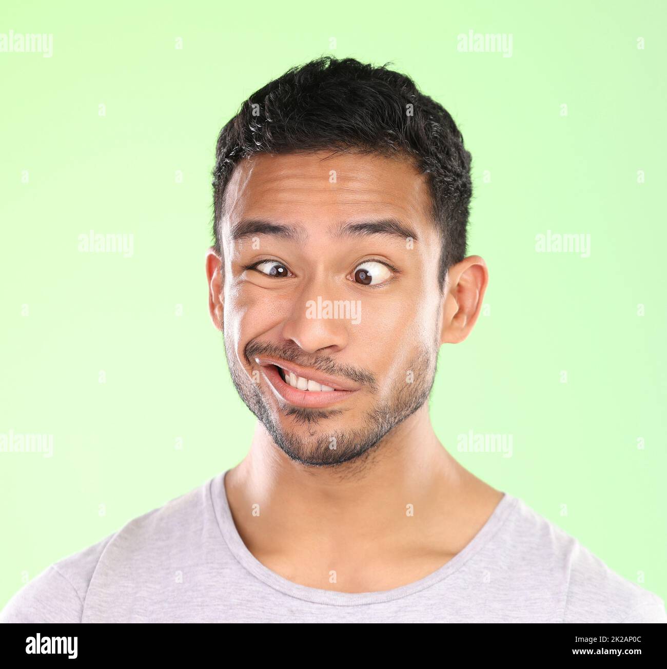 Ah duh. Cropped shot of a handsome young man making a face against a green background in studio. Stock Photo