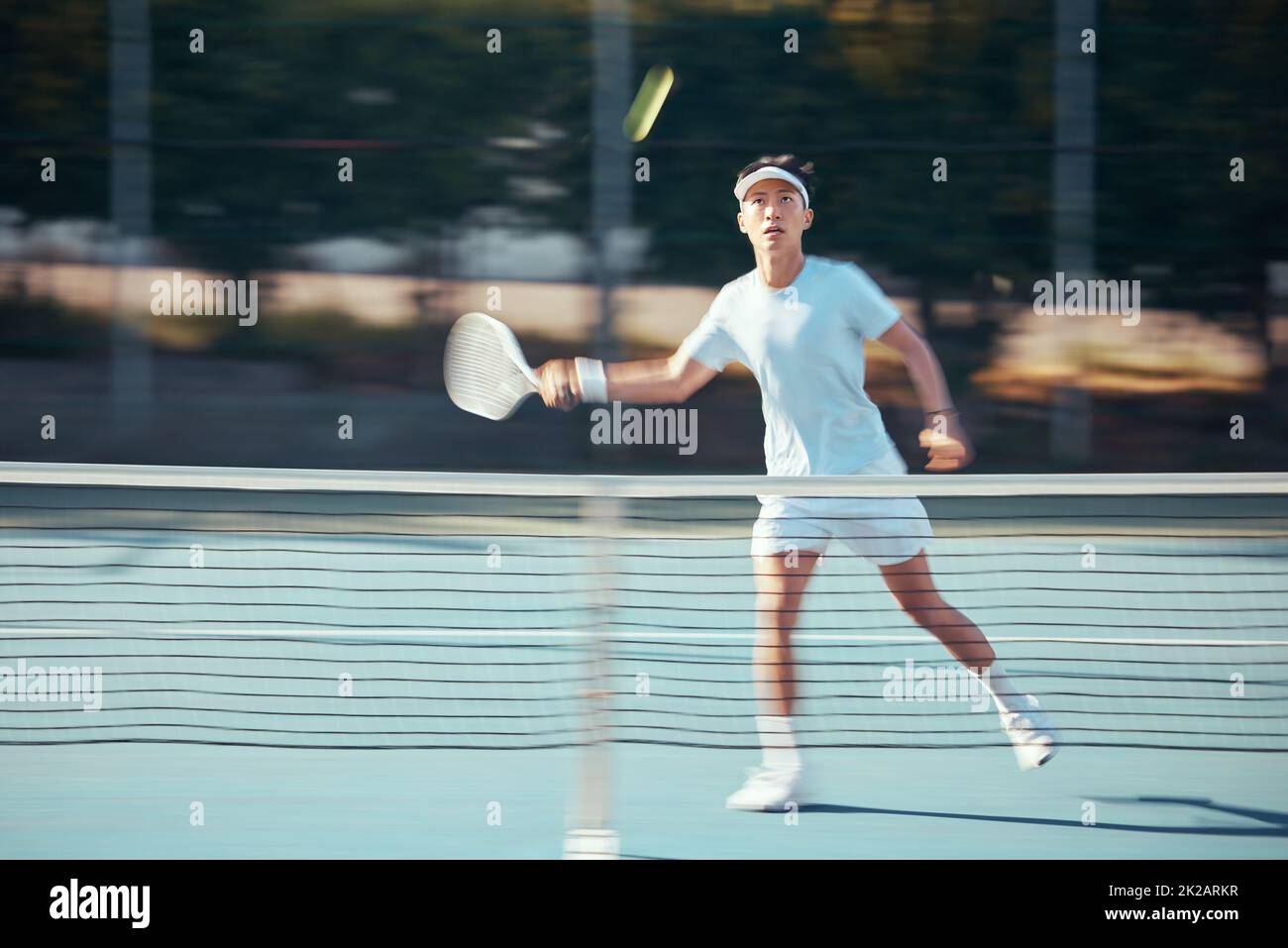 Asian tennis professional training with a racket and playing a game on court. Fit athlete running during a match and play competitive sport workout Stock Photo