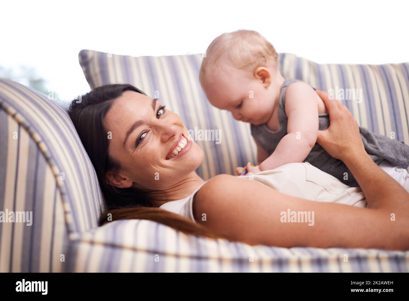 Hes my pride and joy. Portrait of an attractive young woman and her baby girl lying on the sofa. Stock Photo