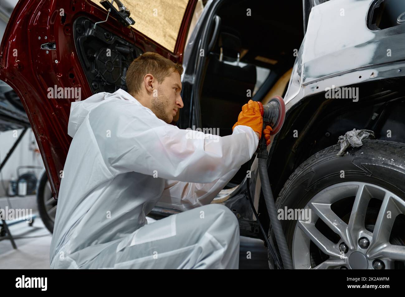 Auto painter polishing plastered car body part Stock Photo