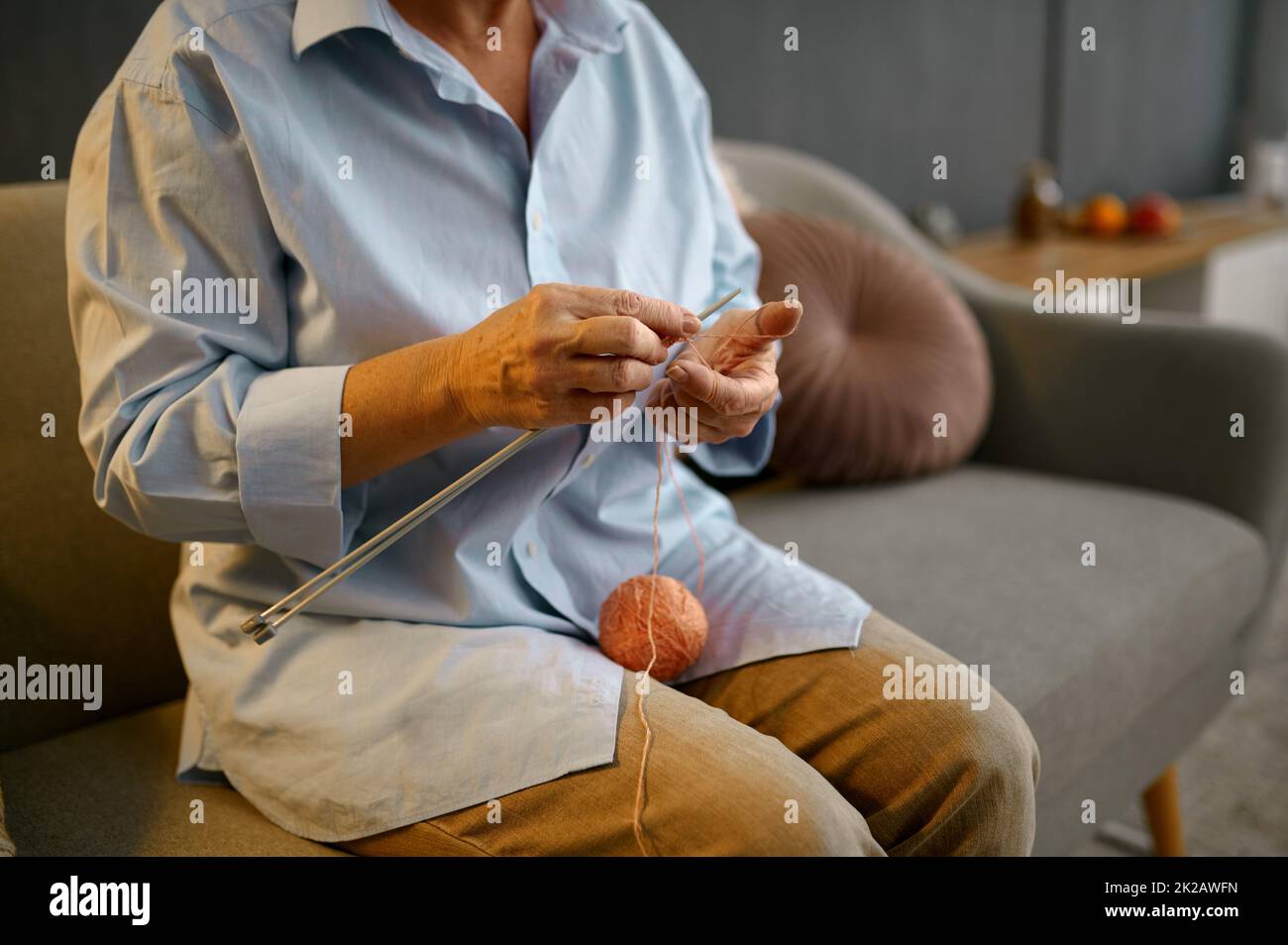 Smiling grandmother knitting sitting at home sofa Stock Photo - Alamy