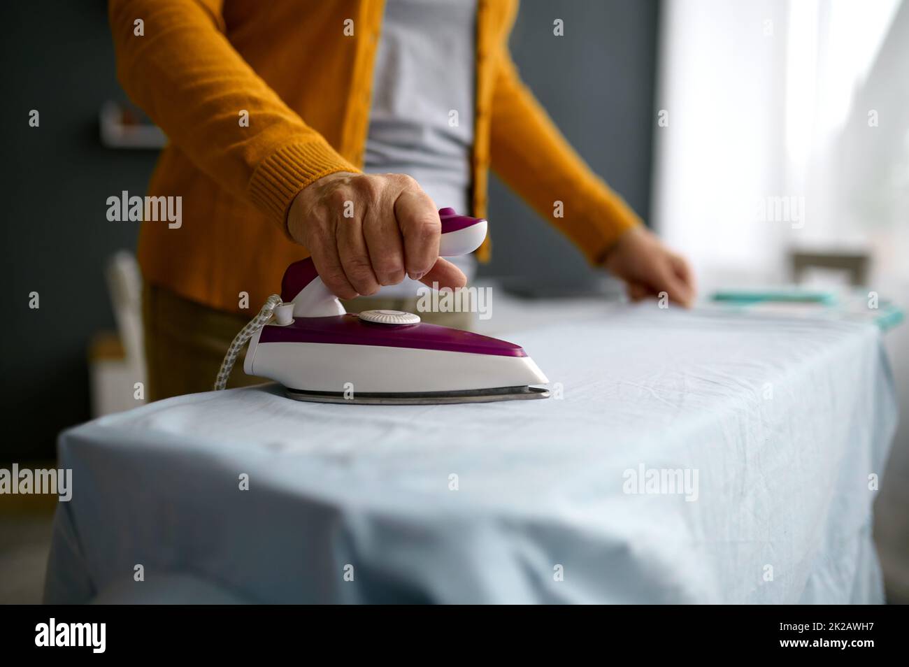 Retired aged woman ironing clothes on board Stock Photo