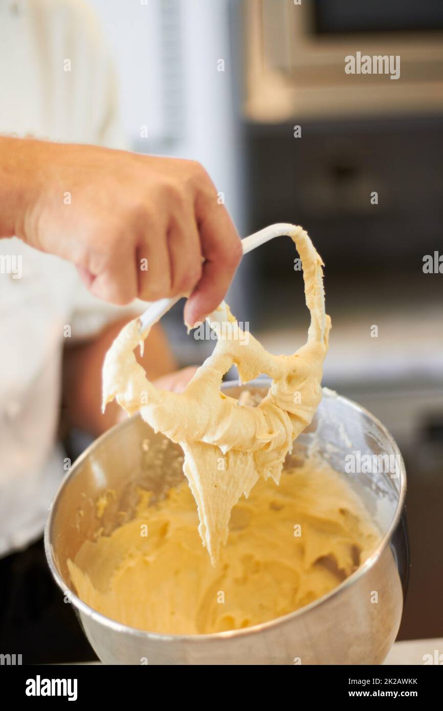 Mixing it until its smooth. A bowl of cupcake batter with the Baker holding up the mixer. Stock Photo