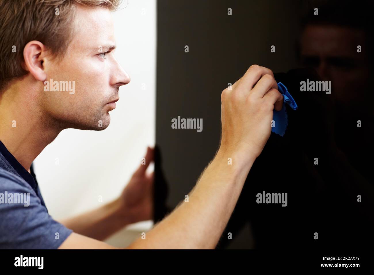 Noticing each speck of dust. Young man cleaning the screen of his smart