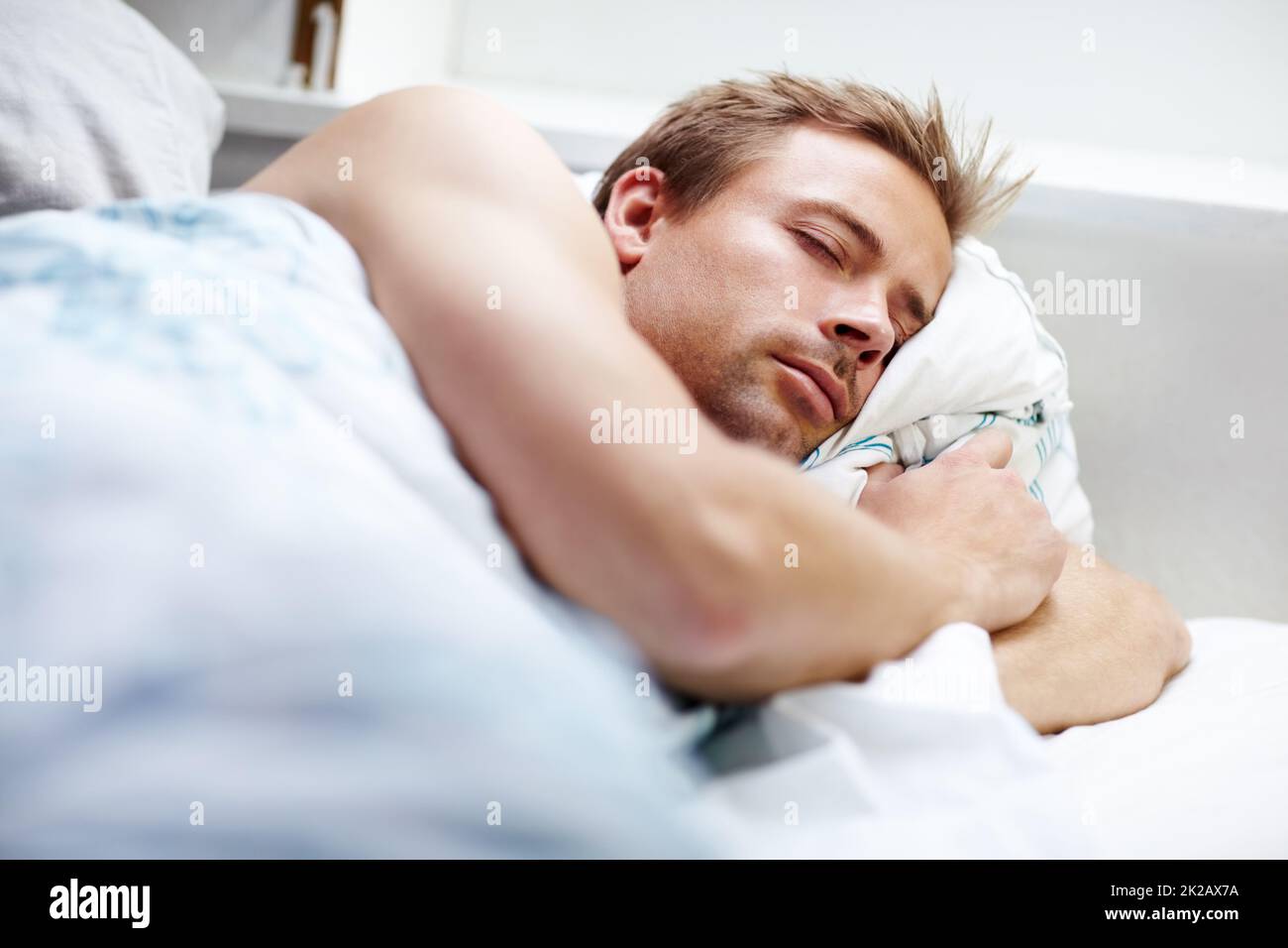 He needs plenty of sleep. Young guy sleeping deeping in bed at home