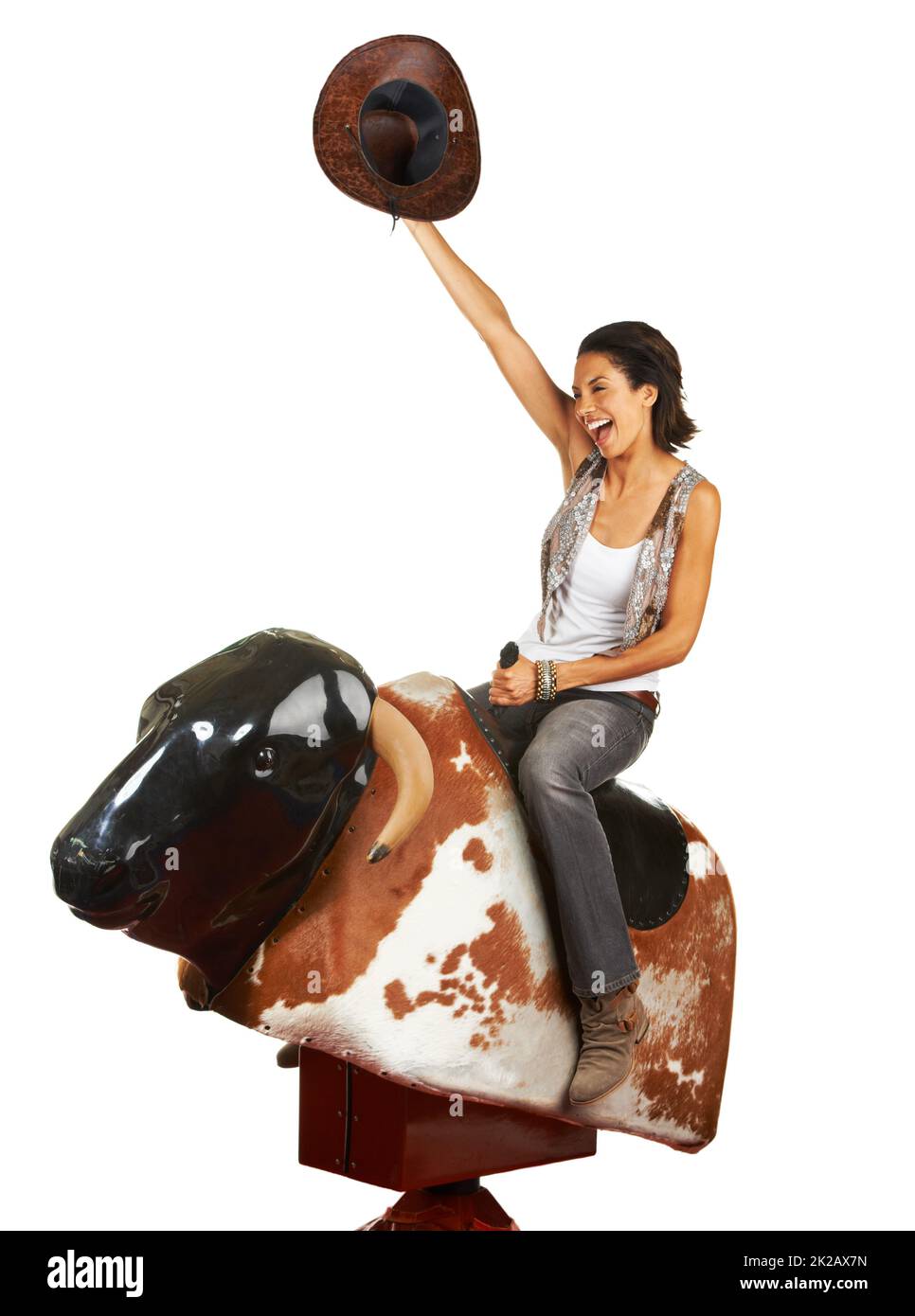Yeehaw. Studio shot of a beautiful young woman riding a mechanical bull against a white background. Stock Photo