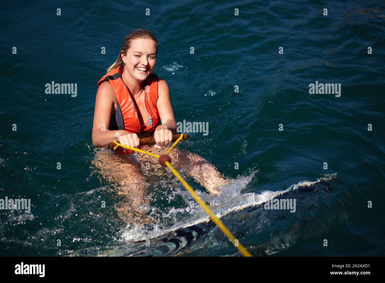 A pretty young woman in the water with a wakeboard wearing a lifejacket. A pretty young woman in the water with a wakeboard wearing a lifejacket. Stock Photo