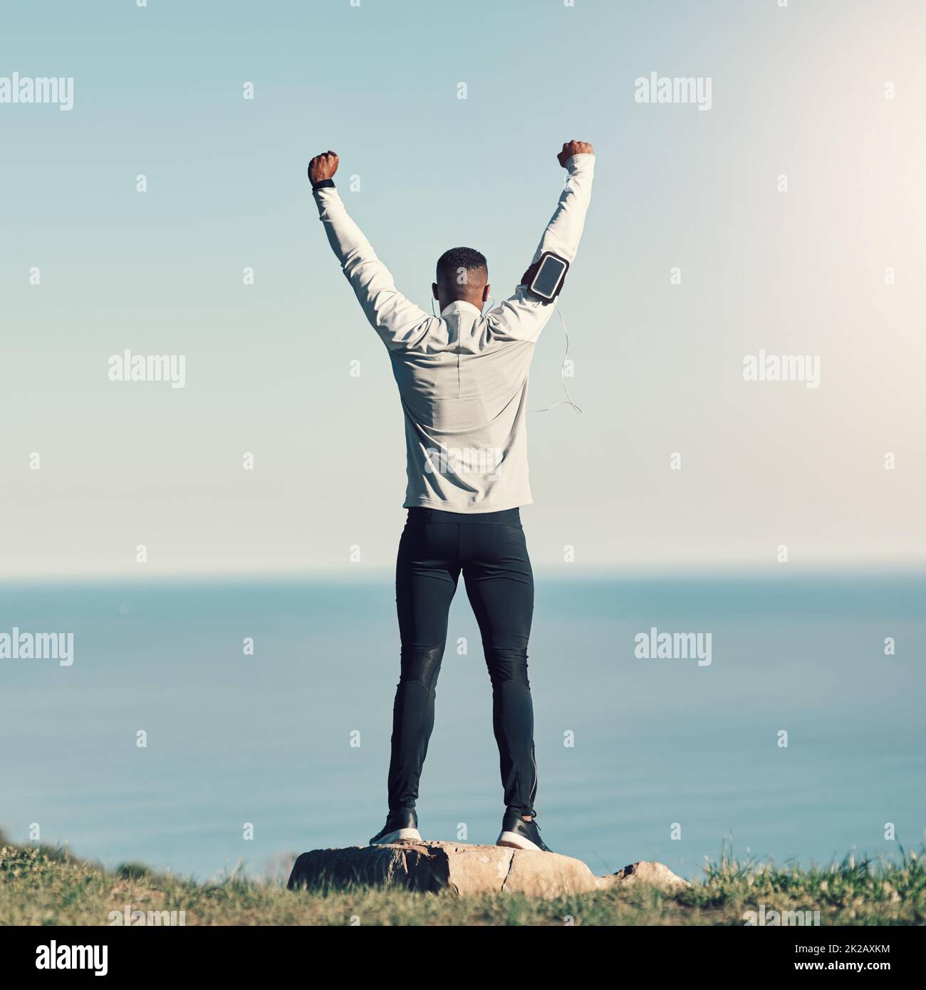 I did it. Rearview shot of an unrecognizable young man standing with his hands raised while exercising outdoors. Stock Photo