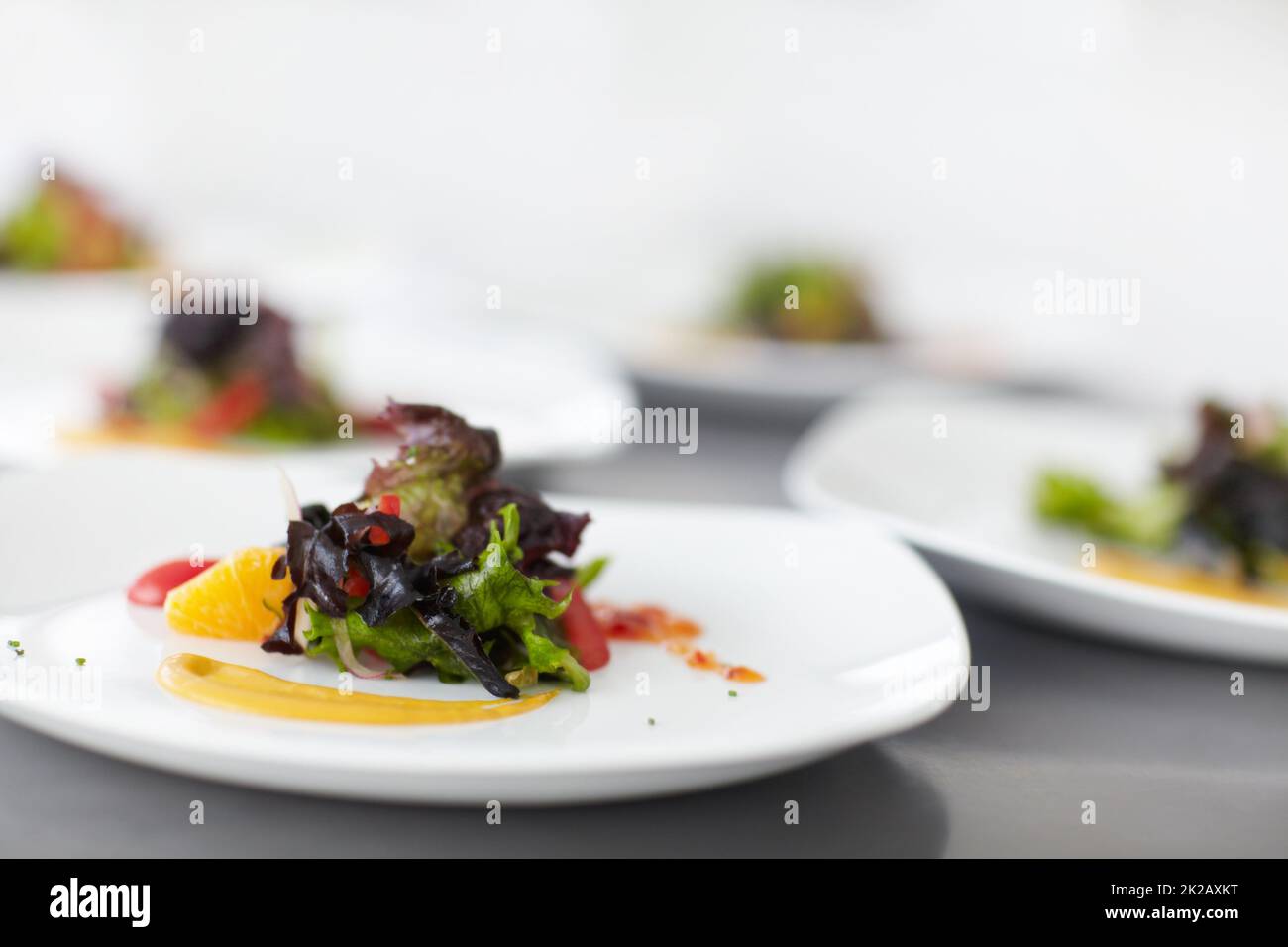 Expertly prepared salad. Multiple plates of well-prepared salad ready to be served - Fine Dining. Stock Photo