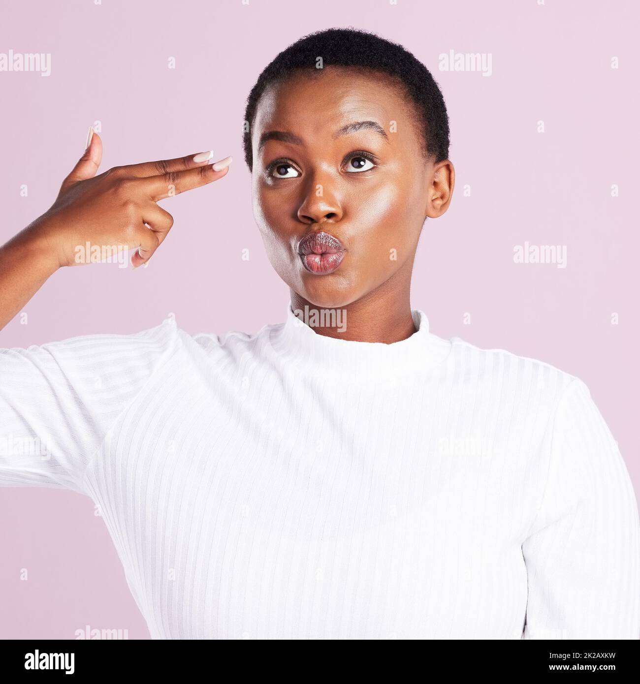 Lifes too short to not be weird. Studio shot of a young woman holding up a finger gun gesture against a pink background. Stock Photo