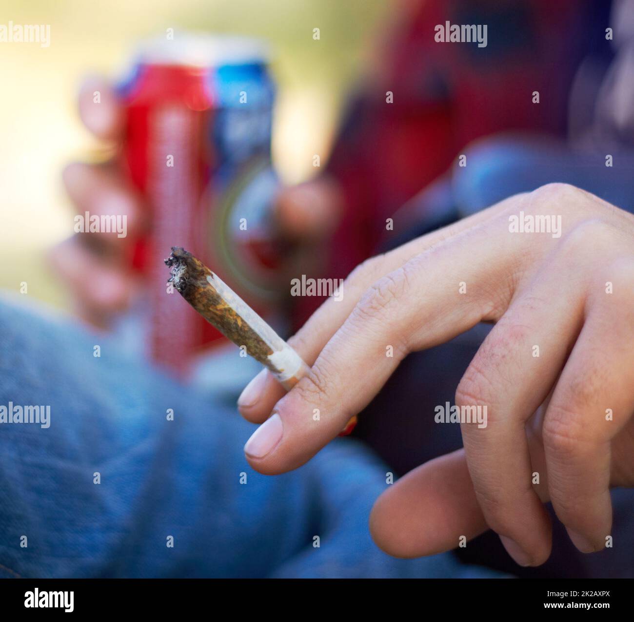 Puffing the day away. Shot of a unrecognizable person smoking a large marijuana joint. Stock Photo