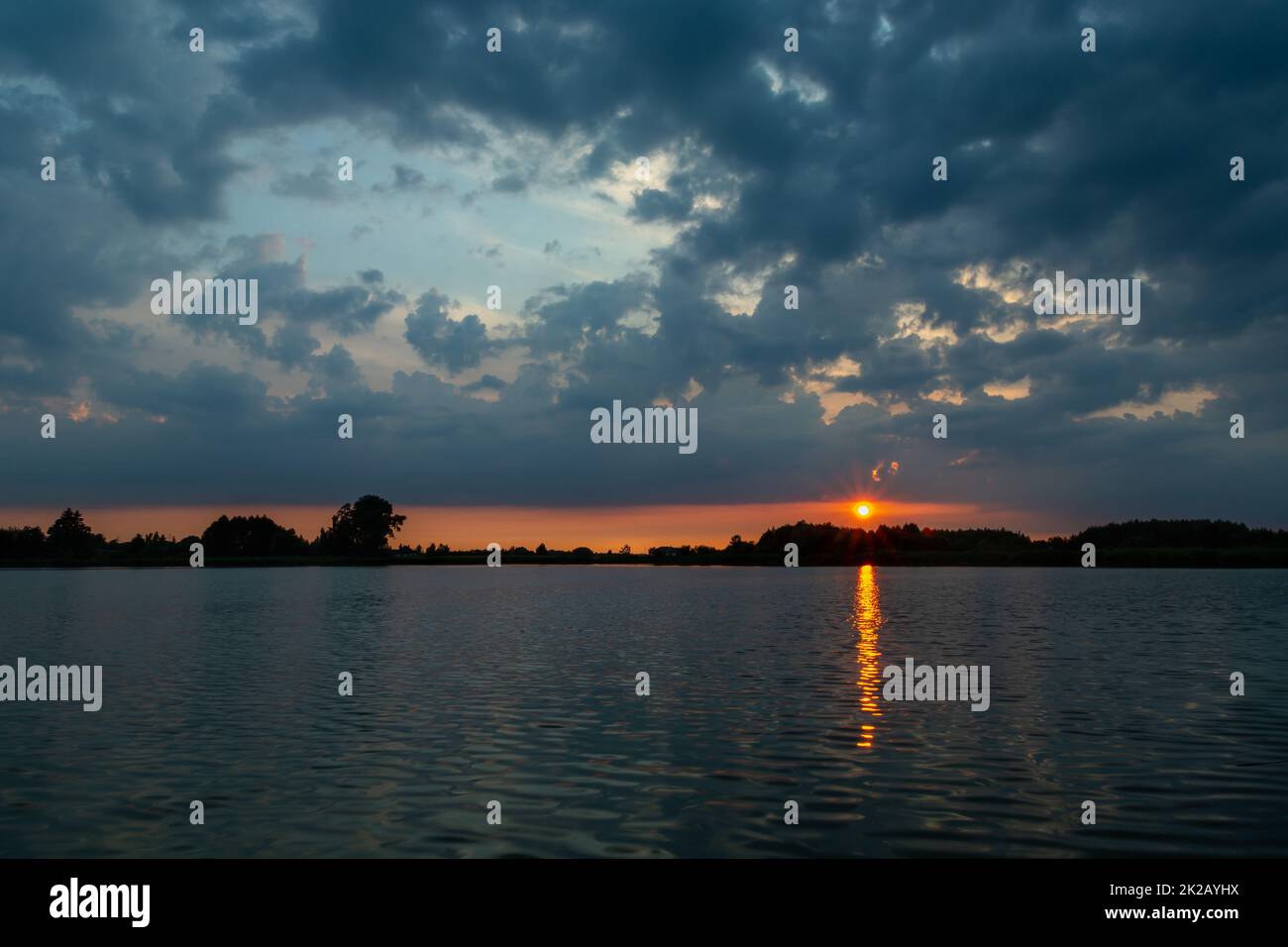 Dark clouds and sunset over the lake Stock Photo