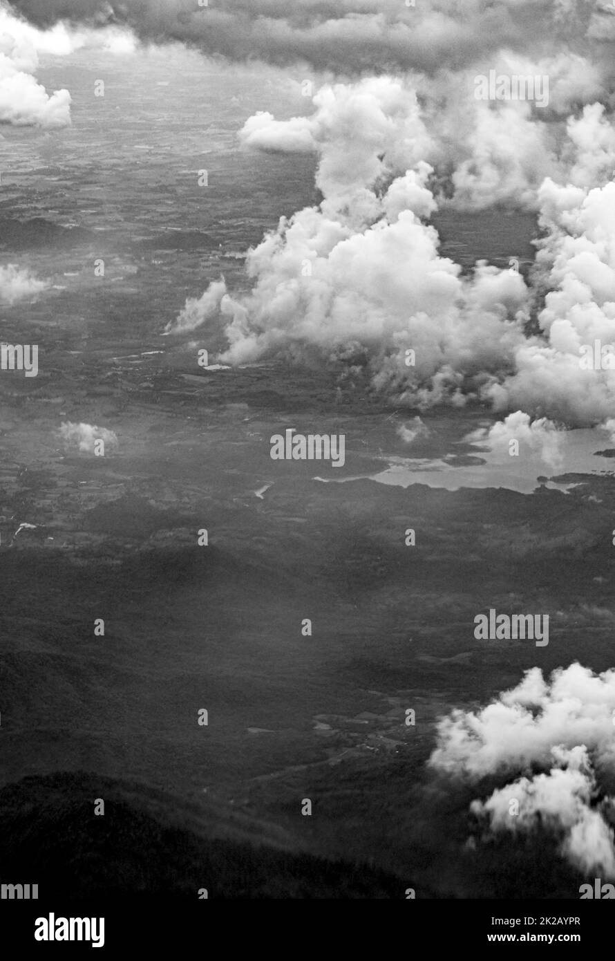 Flying above clouds over countryside of Thailand black and white. Stock Photo