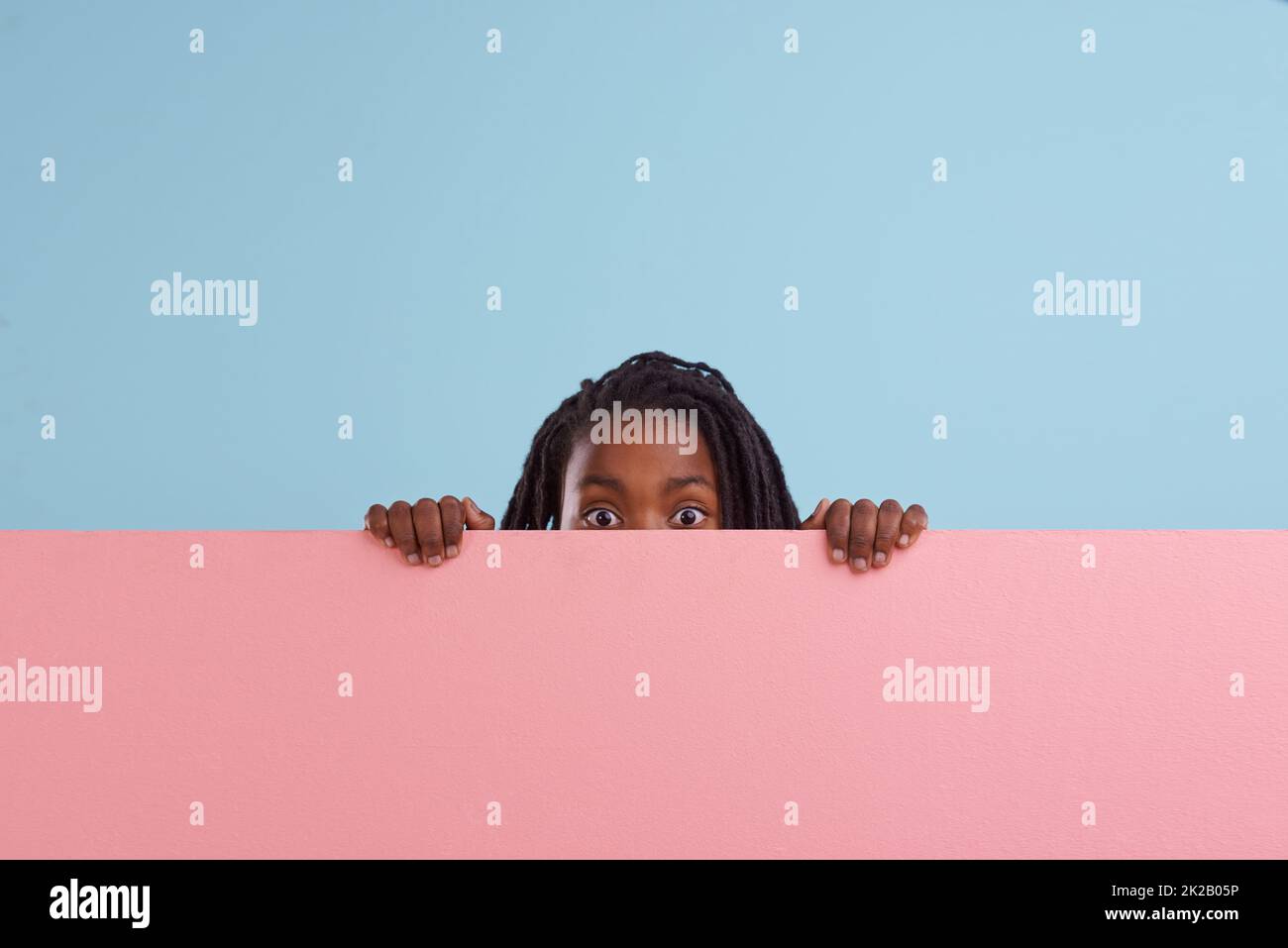 Say what. Studio portrait of a young boy peering from behind a blank signboard. Stock Photo