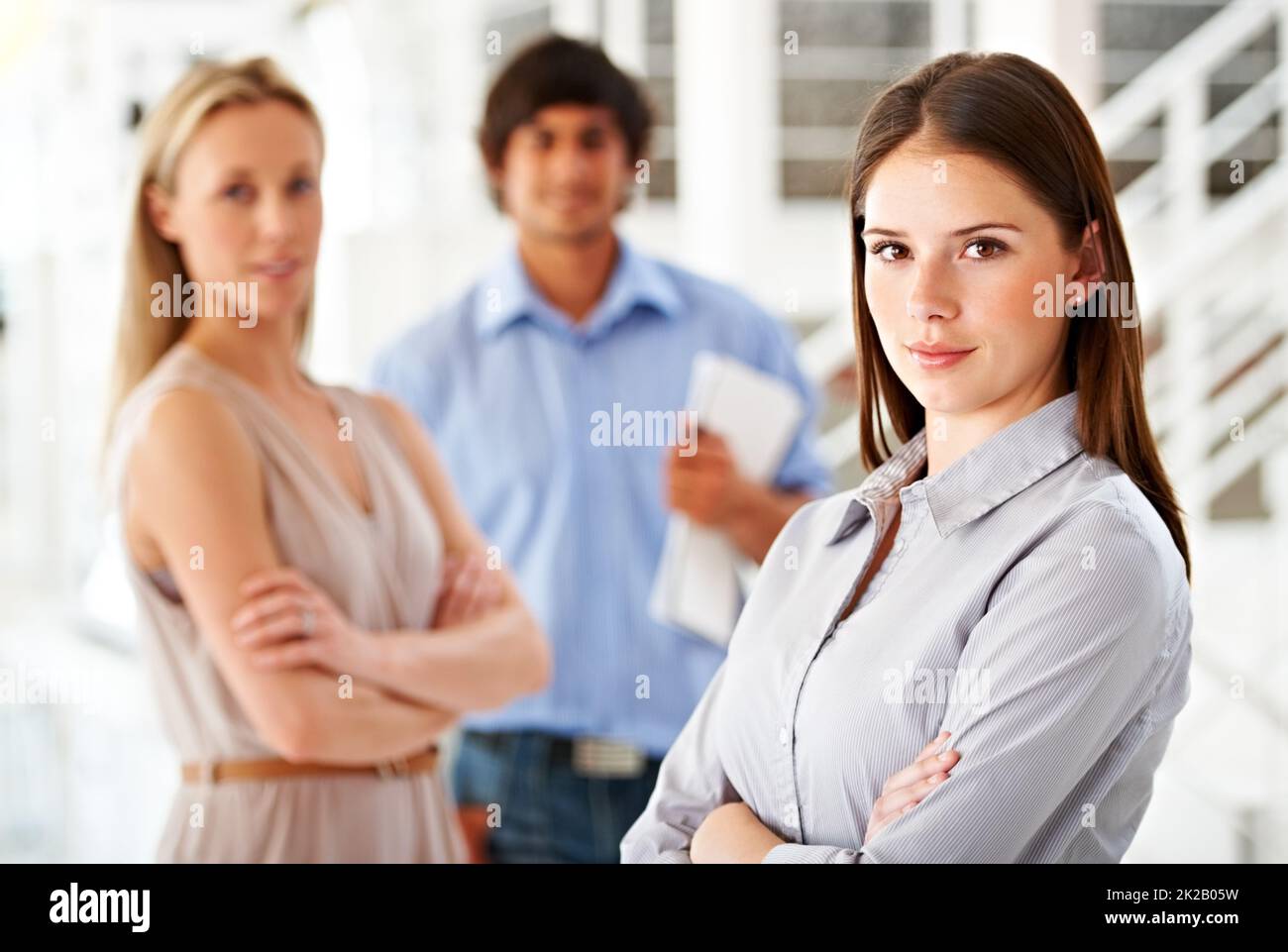 Im taking my team to the top. Shot of a leader smiling at the camera with colleagues blurred in the background. Stock Photo