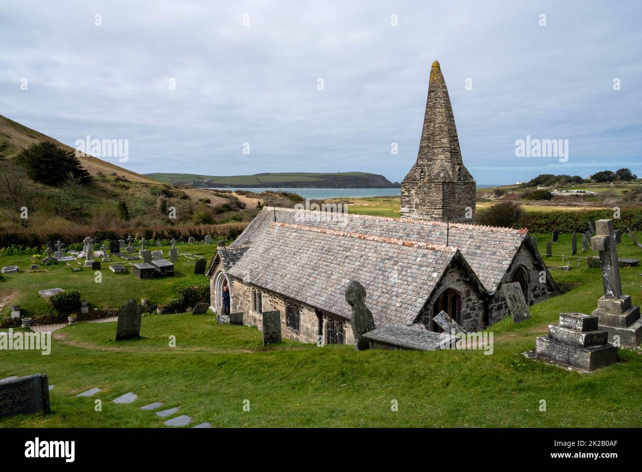 The 12th century St Enodocs Church with Daymer Bay behind. It was buried up to the roof by sand dunes for three centuries. Trebetherick, Cornwall, UK. Stock Photo