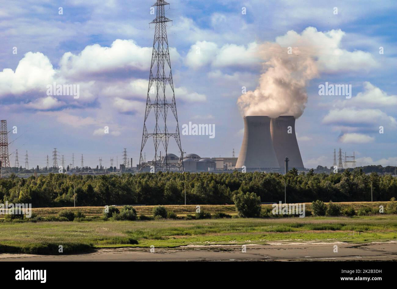 Antwerpen, Flanders, Belgium - July 10, 2022: Sunset on Cooling towers and Doel Nuclear Power plant under blue cloudscape with green nature reserve up Stock Photo