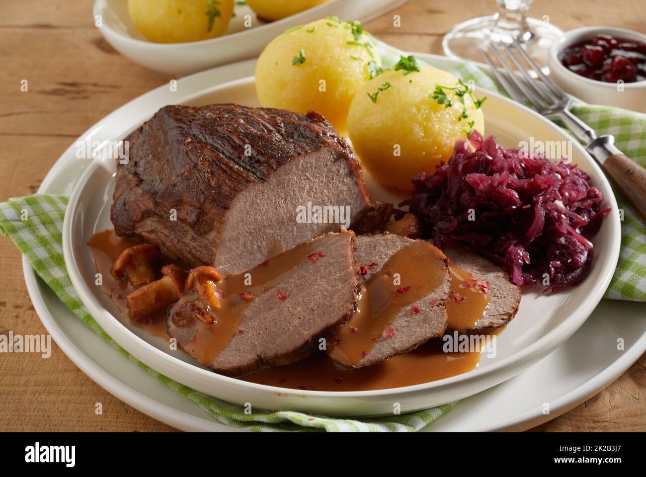 From above delicious roasted venison with mushroom sauce served on ceramic plate near potato dumplings and red cabbage sauerkraut during dinner Stock Photo