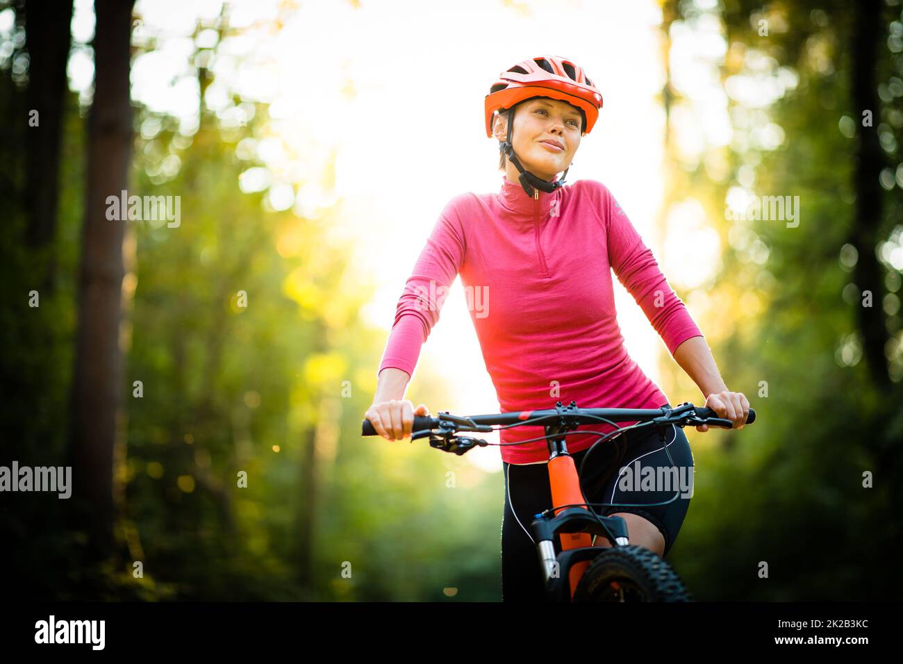 Pretty, young woman biking on a mountain bike enjoying healthy active lifestyle outdoors in summer (shallow DOF) Stock Photo