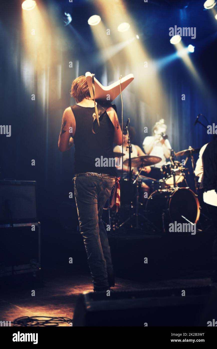 Rocking out. A guitarist on stage with his band beneath strobe lights