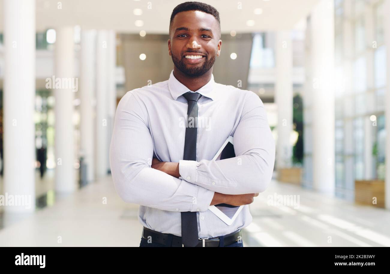 I am not afraid of any work challenges. Cropped portrait of a handsome young businessman standing with his arms folded ad holding a tablet while in the office. Stock Photo