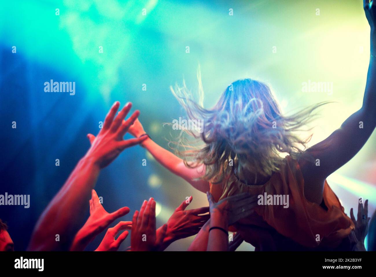 Crowd surfing. A young girl crowd surfing as a band plays one of her favourite songs. Stock Photo