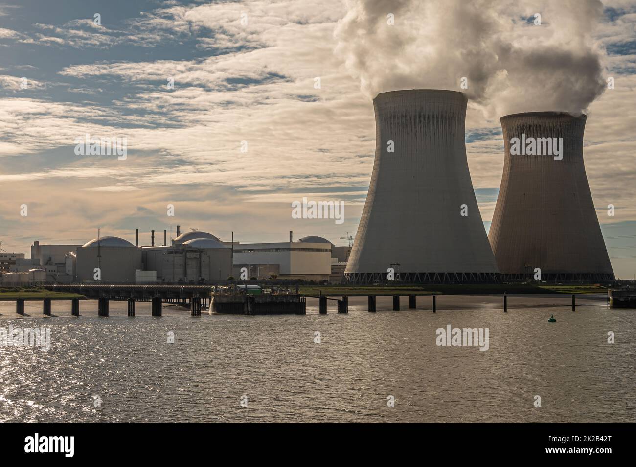 Antwerpen, Flanders, Belgium - July 10, 2022: Closeup, Sunset on Cooling towers and Doel Nuclear Power plant blowing steam into blue cloudscape. Schel Stock Photo
