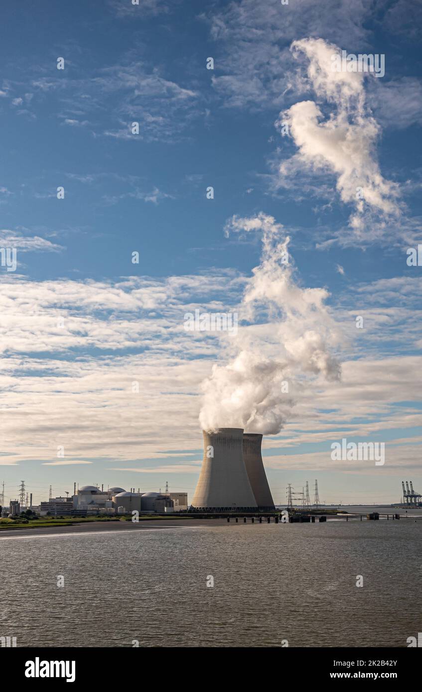Antwerpen, Flanders, Belgium - July 10, 2022: Portrait, Sunset on Cooling towers and Doel Nuclear Power plant blowing steam into blue cloudscape. Cont Stock Photo