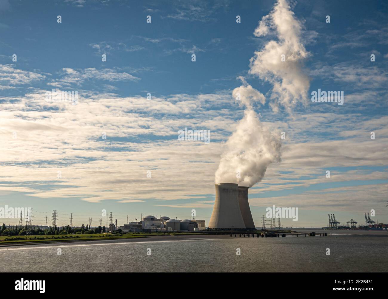 Antwerpen, Flanders, Belgium - July 10, 2022: Sunset on Cooling towers and Doel Nuclear Power plant blowing steam into blue cloudscape. Container Euro Stock Photo