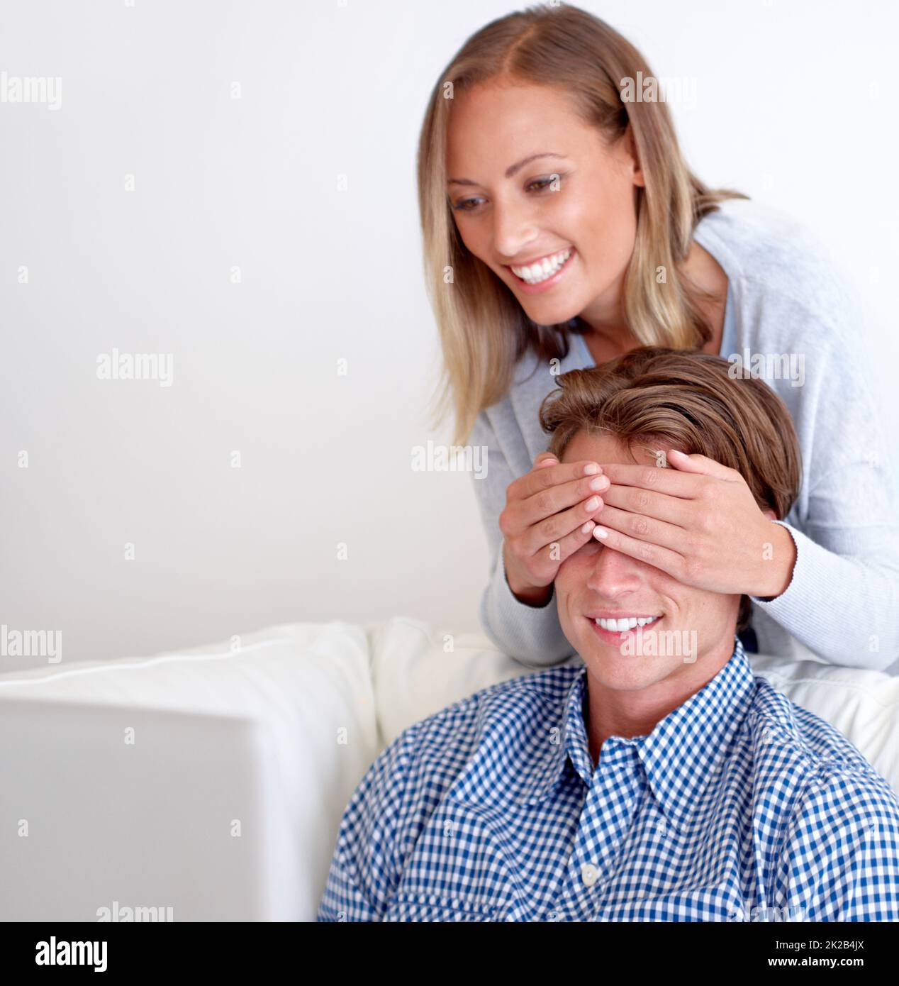 Guess who. A beautiful young woman covering her boyfriends eyes to surprise him. Stock Photo
