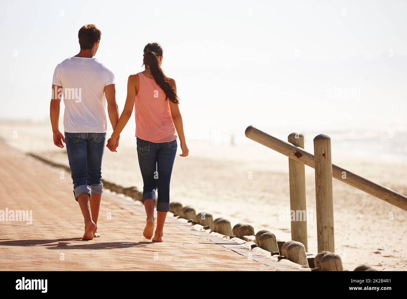 Enjoying a walk down memory lane. Rear view shot of a young couple walking along the beach holding hands. Stock Photo