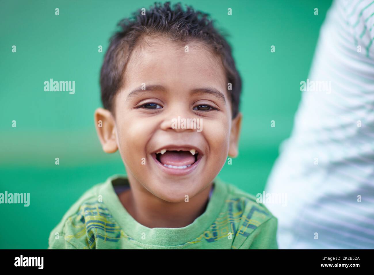His laugh is infectious. Cute little preschooler laughing and smiling at the camera. Stock Photo