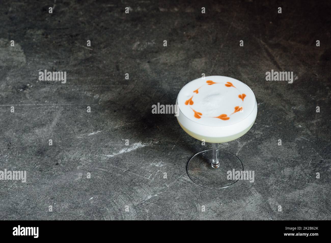 Whiskey Sour with foam froth with heart designs on concrete background