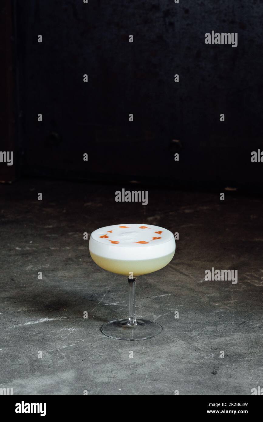 Whiskey Sour with foam froth with heart designs on concrete background